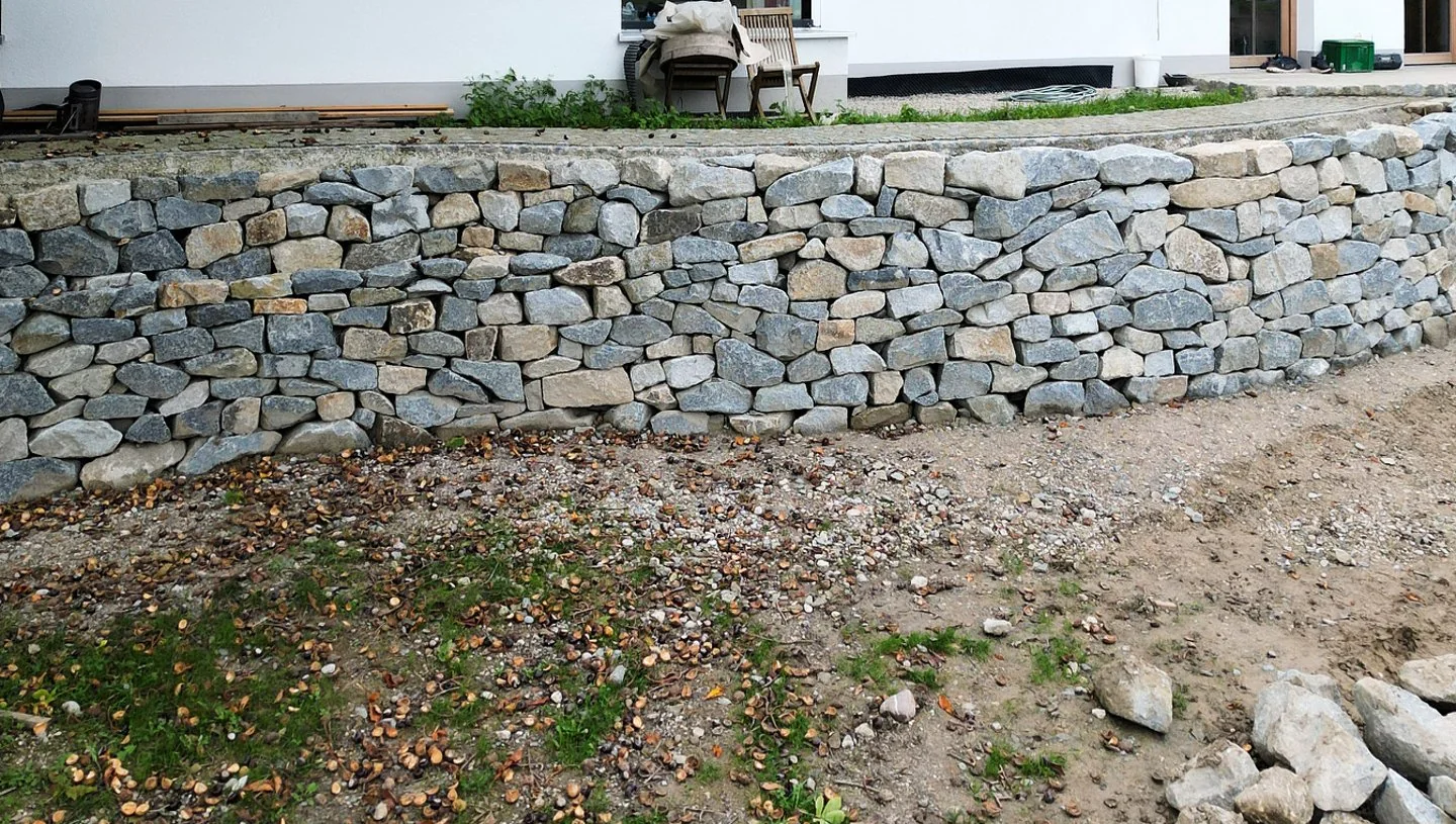 Geschwungene Trockensteinmauer aus Granit als Geländeabfang im Landkreis Erding